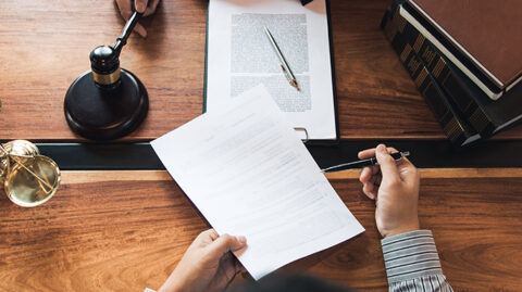 Lawyer and client passing papers over desk feature photo