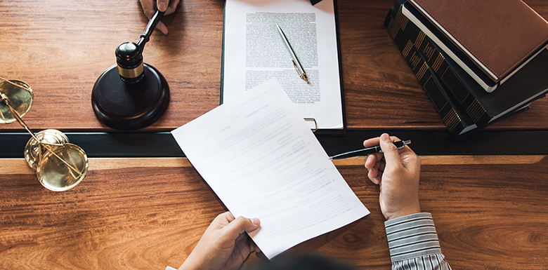 Lawyer and client passing papers over desk feature photo