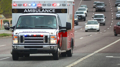 Ambulance with emergency lights driving down road image