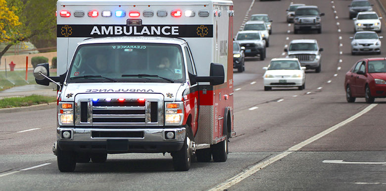 Ambulance with emergency lights driving down road image