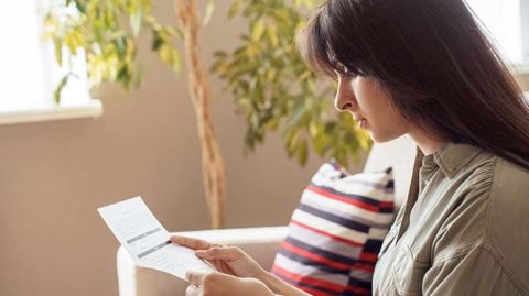 Woman reading paper check from mail