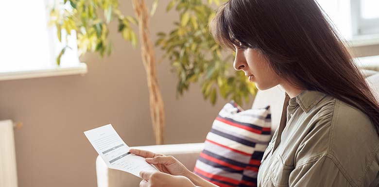Woman reading paper check from mail