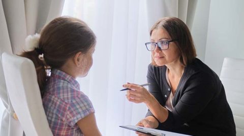 Woman with clipboard talking to young girl