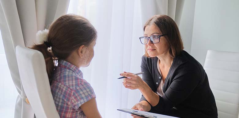 Woman with clipboard talking to young girl