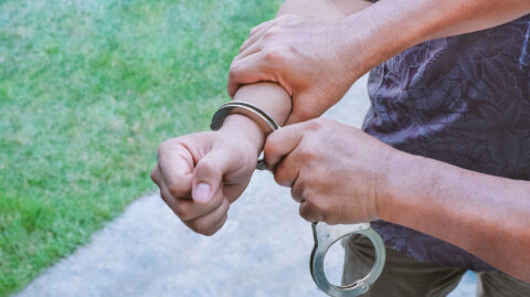 Close up plainclothes policeman's hand handcuffing young man in Perry County, PA